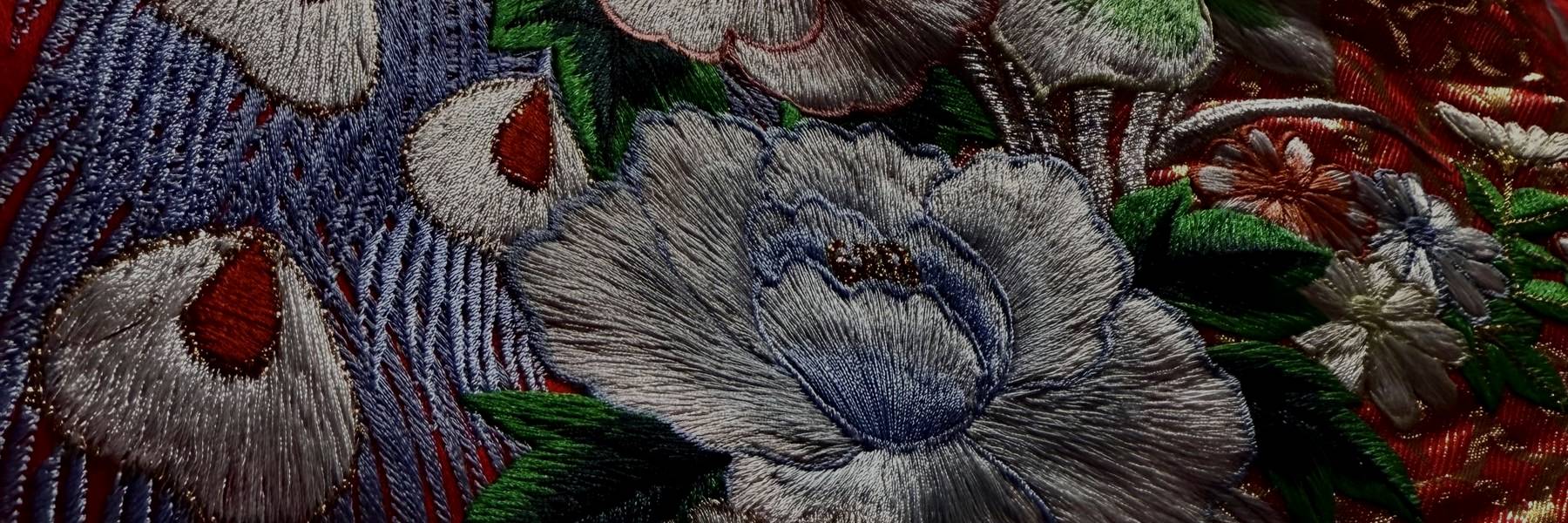 Embroidered peacock feathers and peonies on red silk